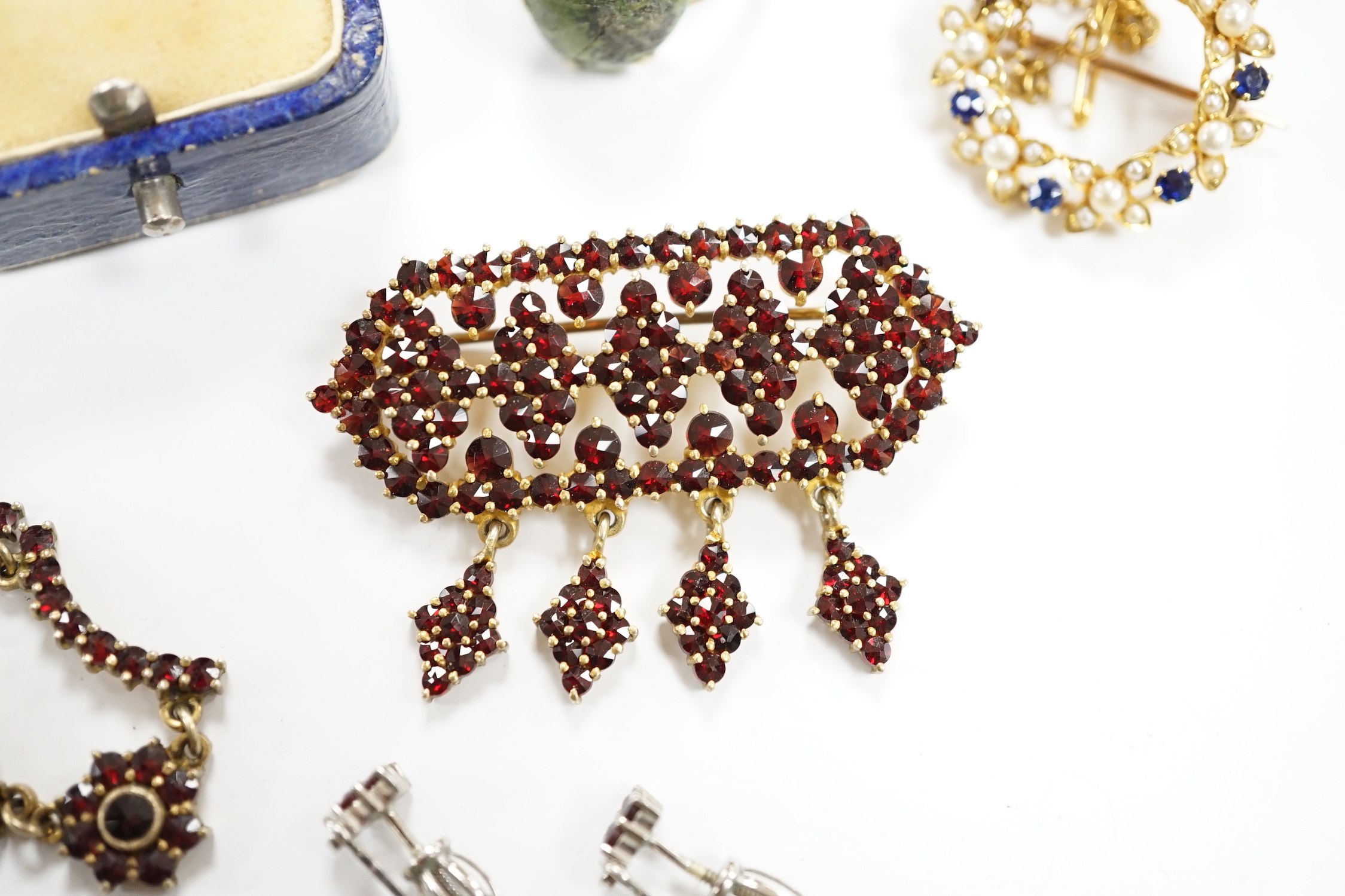 A yellow metal, sapphire and seed pearl cluster set openwork brooch, 23mm, a 9ct and hardstone ring, four items of garnet set jewellery and a pair of jade set ear studs.